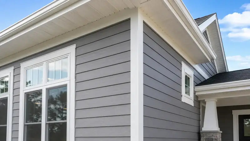 Close-up of gray siding, white corner trim, soffit and window casing